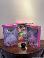 Wide view of three vintage boxed Barbie dolls arranged on a table, showing frontal views of their packaging and display condition.