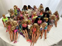 Overview showing the front line of approximately 29 Barbie dolls and 5 Ken dolls wearing various bright vintage costumes.