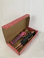 Open cardboard case with both dolls laid inside