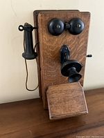 Front left three-quarter view showing oak case, dual bells, mouthpiece and handset