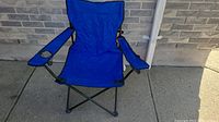 Side angle of folded blue camping chair showing fabric and metal frame.