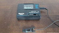 Black Matrix SR-1000V tuner with needle meter and clip-on sensor on wooden surface.