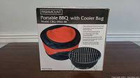 Box showing Paramount Portable BBQ with Cooler Bag, model CBQ-9902-BK, highlighting features and dimensions.
