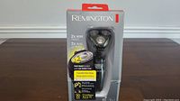 Image of Remington rotary shaver in original boxed packaging showing front with brand and product features.