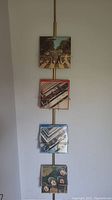 Full view of spring loaded record holder mounted from floor to ceiling with four Beatles LP records displayed