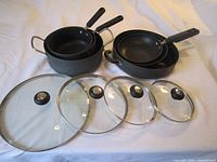 Full set of 3 pots, 3 skillets, and 4 glass lids laid out showing nesting and size variations.