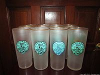 Twelve frosted Colorado Centennial glasses with gold rims, showing front emblem and uniform outline