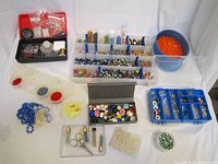 Overview photo of assorted bead jewelry making supplies including beads sorted in plastic containers, tools, findings, and stringing materials on white background.