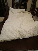 Full view of the white polyester fill comforter spread over a table to show its size and condition.
