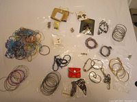 Wide view of mixed jewelry assortment including bracelets, earrings, pendants, and necklaces spread on flat surface.