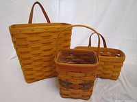 Three Longaberger baskets shown together on white background, displaying different sizes and handle styles.