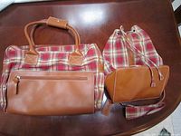 Photo showing both the Longaberger tote bag and sling pack placed on a wooden surface, highlighting the plaid fabric and leather accents.