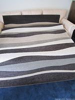 Full view of the 5x7 rug displaying the multi-colored wave stripe pattern in dark and light neutral tones.