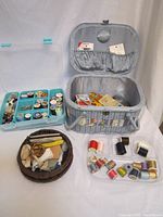 Full view of sewing basket with compartments and all sewing supplies displayed around it including thread, scissors, and tools.