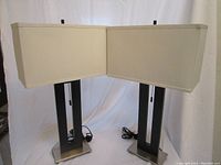 Both modern table lamps shown side by side with black metal open-frame bodies, nickel bases, and white rectangular shades.