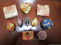 10 assorted trinket boxes arranged on wooden surface showing shapes and decorative artwork