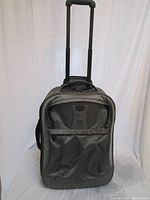 Full front view of gray Tumi carry-on luggage with extended telescoping handle and front zippered pocket