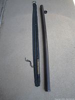Photo showing the full fly rod disassembled with its black fabric sleeve and hard cylindrical case next to it.