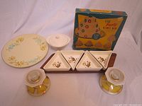 Photo showing MCM candle holders with glass covers, ceramic round floral plate, small covered dish, divided serving dish with squirrel illustrations, and boxed aluminum cake pans