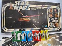 Photo of the game box with Star Wars title and characters on the lid, as well as the colored character playing pieces displayed in front on the game board holder.