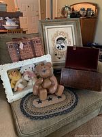 Full lot showing embroidered raccoon framed art, wooden bear sculpture, curved storage box with lid open, 3D display frame with stuffed toys, and handwoven basket.