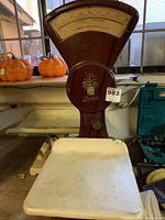 Overall photo of the antique Berkel scale showing its wooden structure, dial, white weighing platform, and the metal weigh scale behind it.