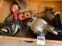 Overview of tools in wooden box including Shop Mate belt sander, various sanding discs and wire brushes, and red angle grip sander tool.