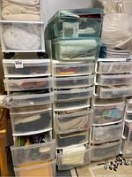 Wide view of many plastic drawer organizers stacked with various folded fabrics and craft supplies.