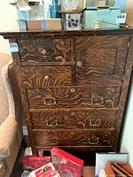Front view of wooden dresser showing multiple drawers with mixed knobs and pull handles, distinctive cross-grain wood pattern.