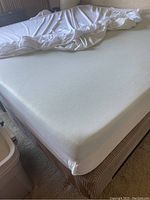 Top view showing memory foam mattress with fitted sheet partially removed revealing mattress surface and a few stains.