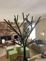 Overall view of black metal coat tree in living room showing tree-shaped branch design