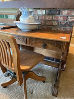 Front view of oak desk with two carved drawers, hinged back top and ceramic pitcher and basin displayed on top