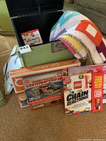 Green wooden box by Pier 1 open showing the child-sized quilt and a Lego Mini Bean Machine booklet inside, along with Toy and Game boxes in front.