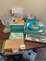 Chip and dip bowl, measuring spoons, serving cutlery and glassware arranged on wooden table, some boxed