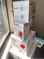 Stacked boxes showing the Beaumark stainless steel sangria or gravy server, Pier 1 Imports tasting party mini shots set, Libbey mini wine glasses, and mini margarita glasses boxed sets.