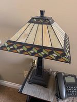 Full view of Tiffany style table lamp on side table, showing the stained glass shade and metal base.