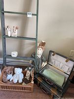 Overall view of lamp, tray with stuffed animals, wooden ladder, Willow Tree figurines, vintage clock, and vintage suitcases.