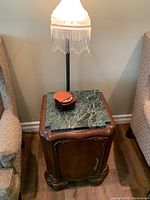 Vintage wooden side table with ornate carved details and green marble top. Small cabinet door with key handle shown.