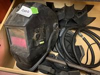 Full view of black welding helmet in drawer with red viewing window.