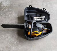 Chainsaw seated inside open hard plastic carrying case viewed from above