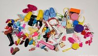 Wide view of multiple colorful vintage Barbie doll shoes and accessories spread out, showing variety of footwear styles and sizes.