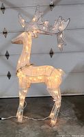 Front-side view of the lit reindeer decoration showing the glitter antlers and wrapped string lights.