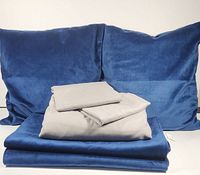 Grey duvet cover, two grey pillow shams stacked on navy blue bed runners, two navy blue throw pillows behind