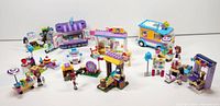 Overview of assembled LEGO Friends sets showing various vehicles, stalls, and mini-figures arranged on a white surface.