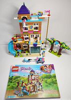 Front and full view of the assembled LEGO Friends Friendship House with all included accessories and instruction book shown in foreground.