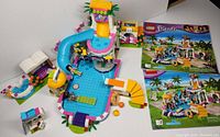 Full assembly of LEGO Friends Heartlake Summer Pool set 41313, including pool, slide, swim-up bar, and instruction manuals visible.