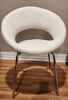 Front view of white faux leather chair showing the open back design, curved seat, and chrome metal legs.
