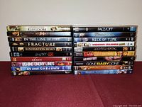 Stacked DVDs showing spines of 20 different movies including action, drama, and comedy titles.