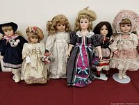Group photo of all 6 vintage porcelain dolls lined up, dressed in detailed period costumes.