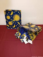 Single large gift bag standing upright showing gold sun and crescent moon patterns on dark blue background